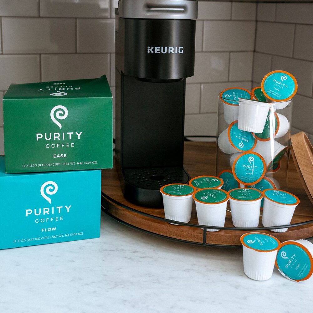 Purity coffee pods with a pod coffee brewer on a wooden turntable