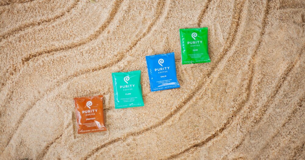 Purity coffee sachets on a sandy background